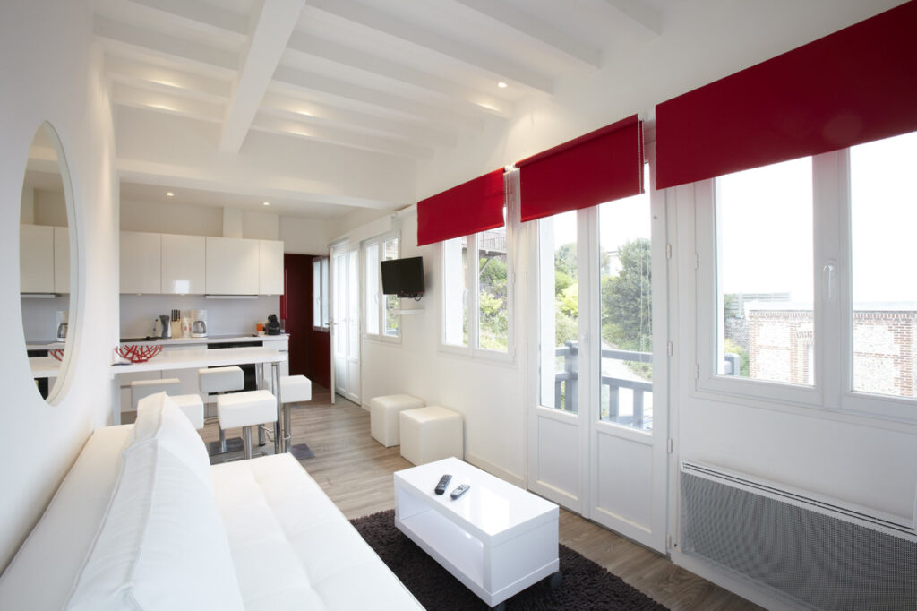 Séjour lumineux du Gîte Gabrielle à Pourville-sur-Mer avec cuisine ouverte, coin salon et vue sur le jardin