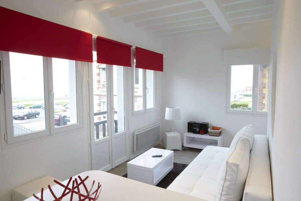 Séjour lumineux du Gîte Gabrielle avec canapé blanc, grandes fenêtres et vue sur la mer