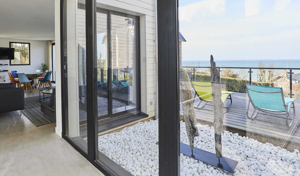 Terrasse avec transats et vue mer depuis la Villa Gabrielle, gîte contemporain à Pourville-sur-Mer proche de Dieppe.